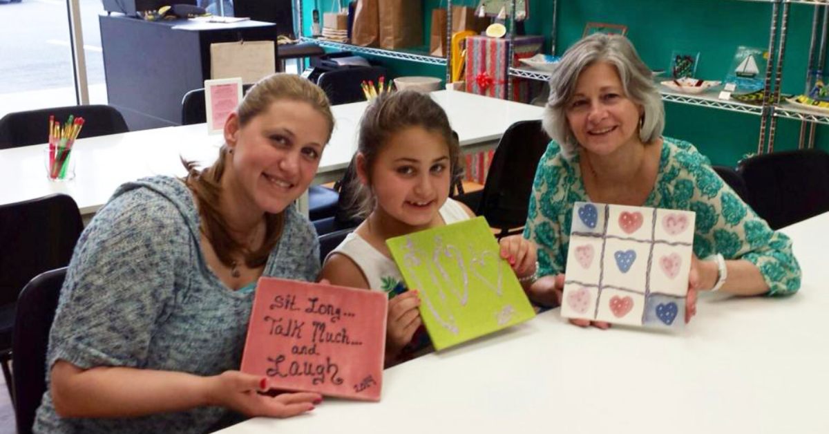 two women and a girl holding up paintings