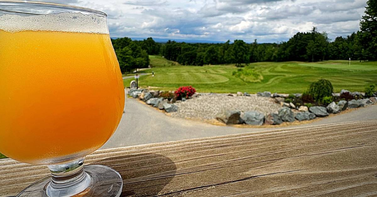 beer glass held up against golf course
