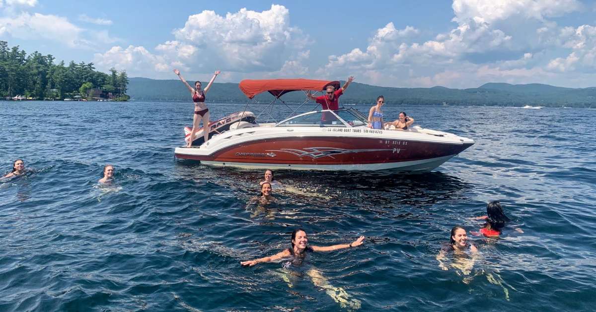 people swimming in a lake by a boat
