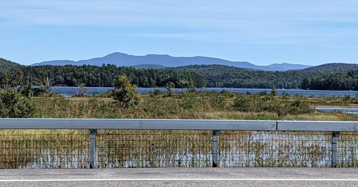view of water and mountains from road in tupper lake