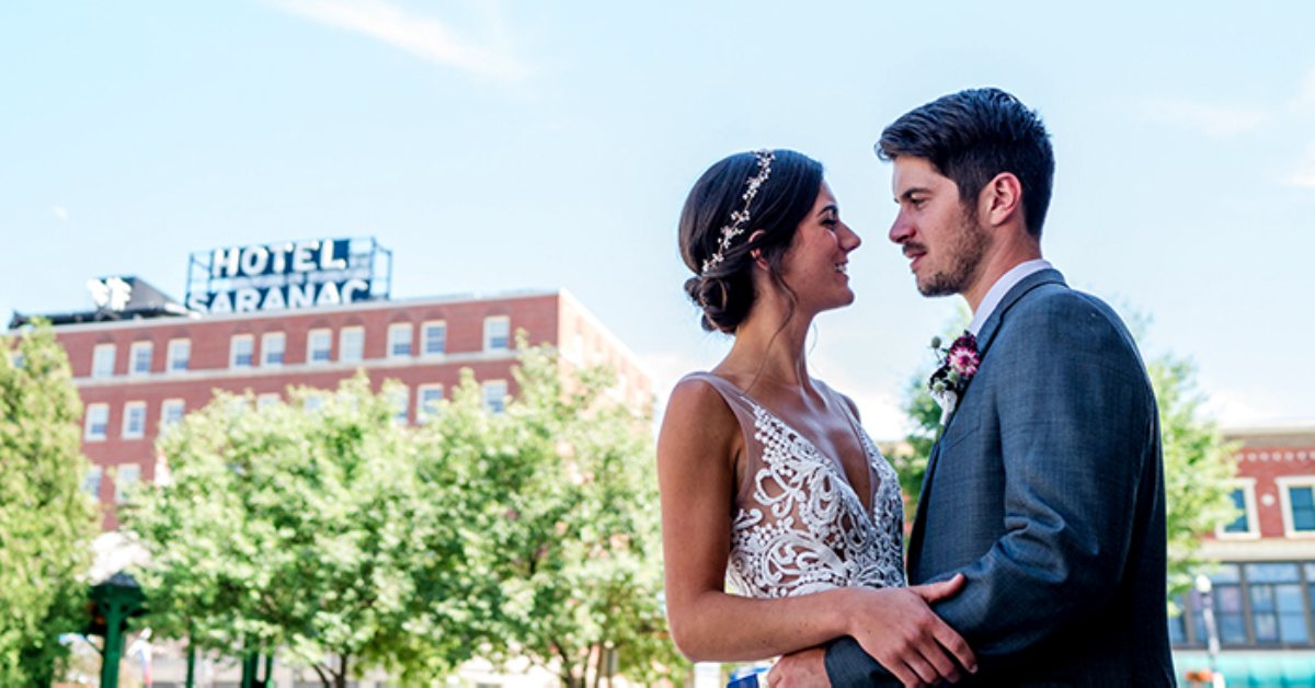 bride and groom embracing with hotel saranac in the background