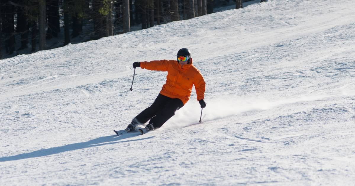 man in orange coat skis