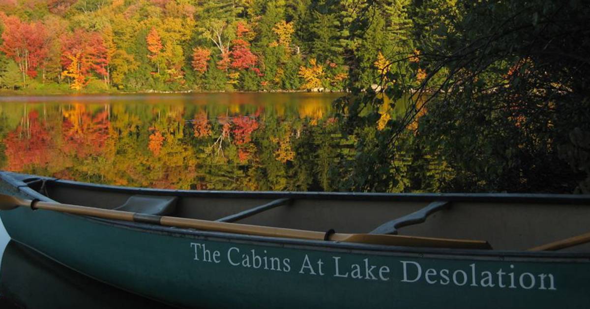 canoe by lake and fall foliage that says the cabins at lake desolation