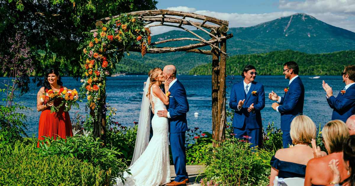 couple kissing by lake with mountains in the background