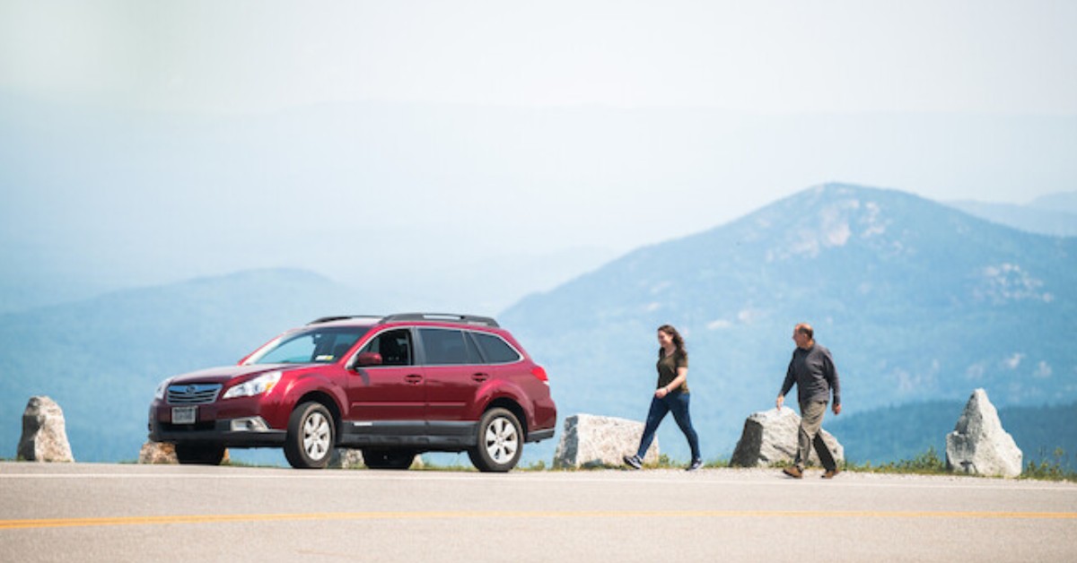 people with red car on mountain highway