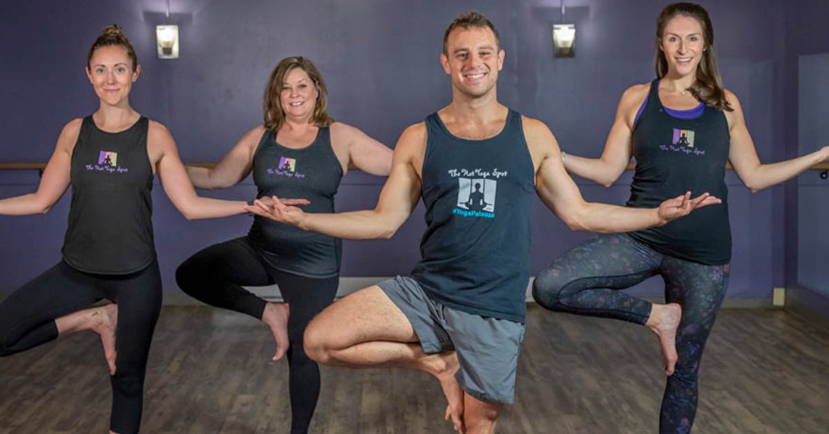 three women and a man doing a yoga pose