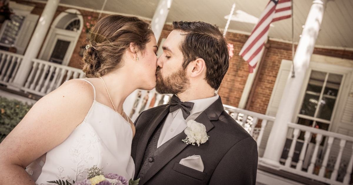 bride and groom kissing outside house