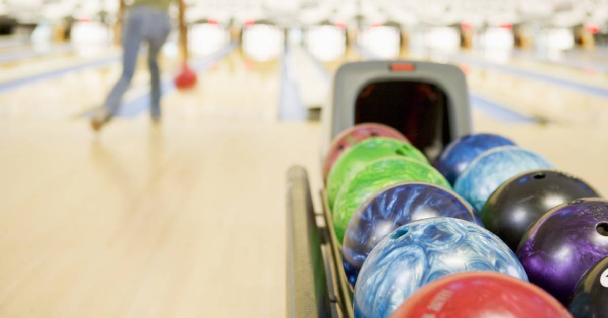 woman bowling in background, bowling balls in foreground