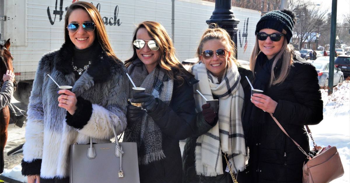 four women in winter clothes holding up chowder samples