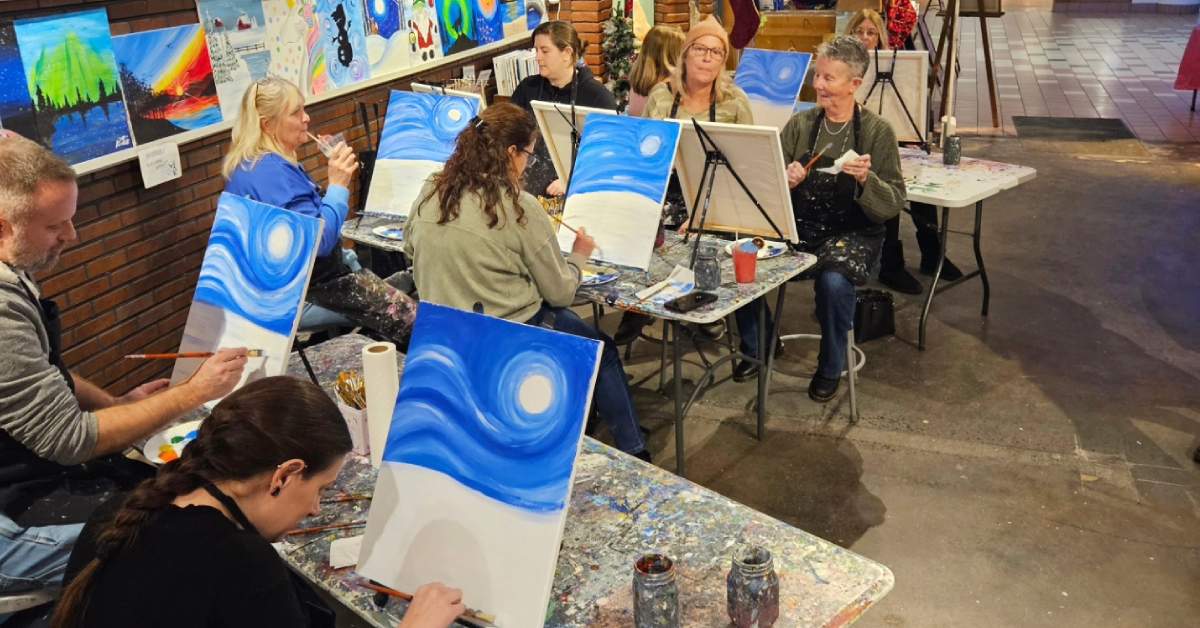 people painting at desks in a studio