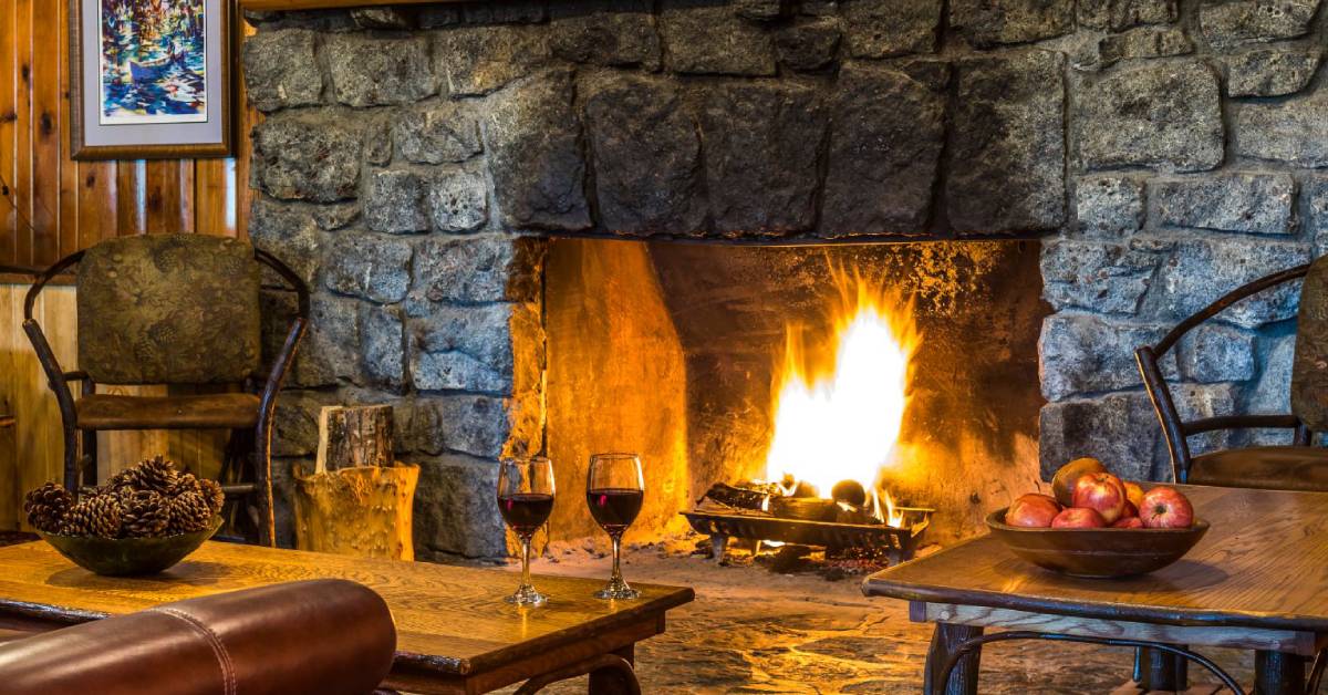 two glasses of red wine by fire in fireplace