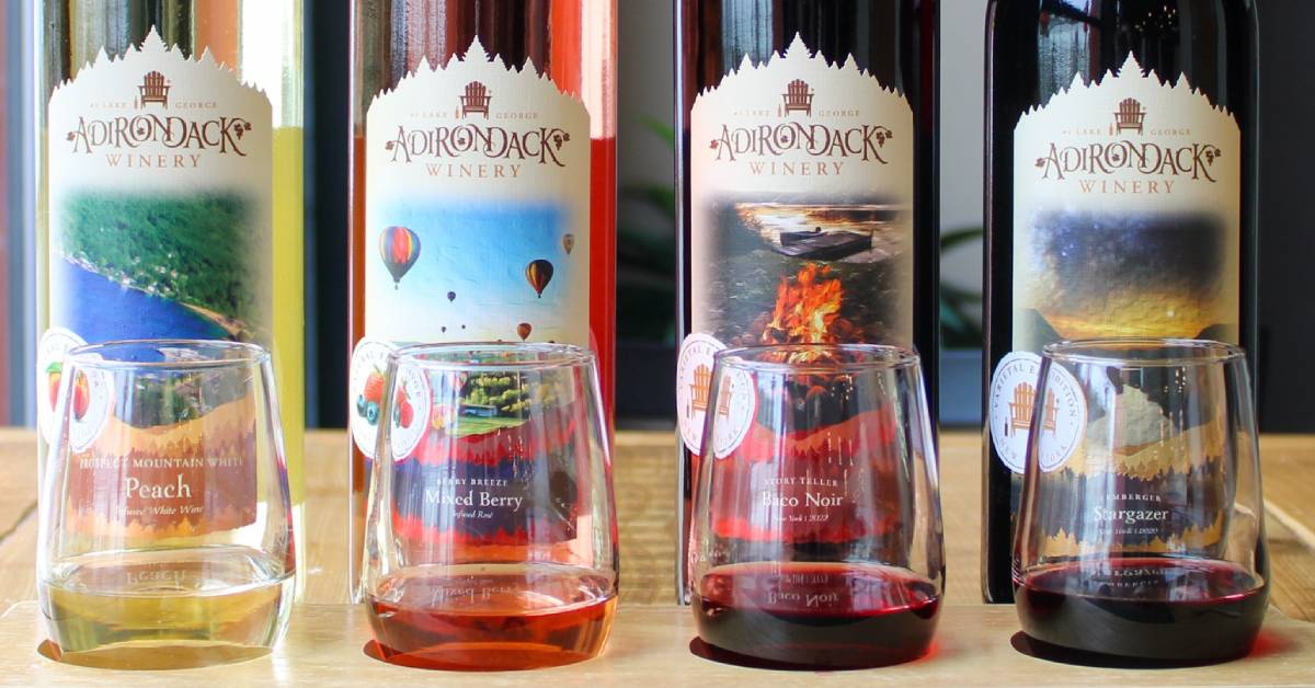 four bottles of adirondack winery wine with glass of each in front