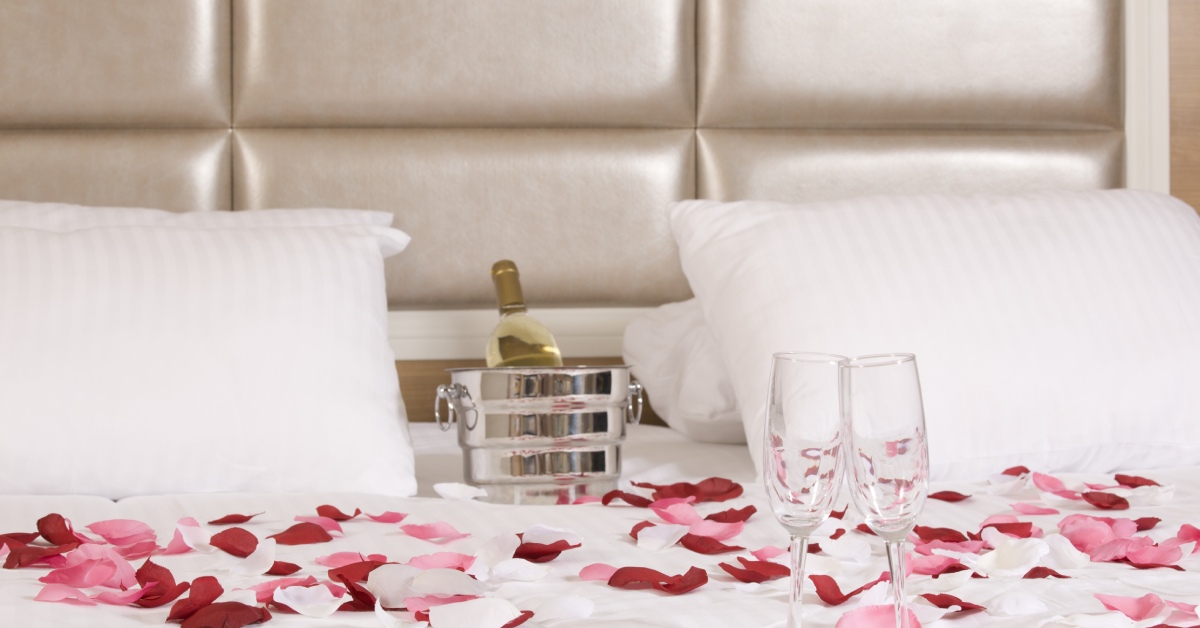 hotel bed with champagne and red/pink flower petals