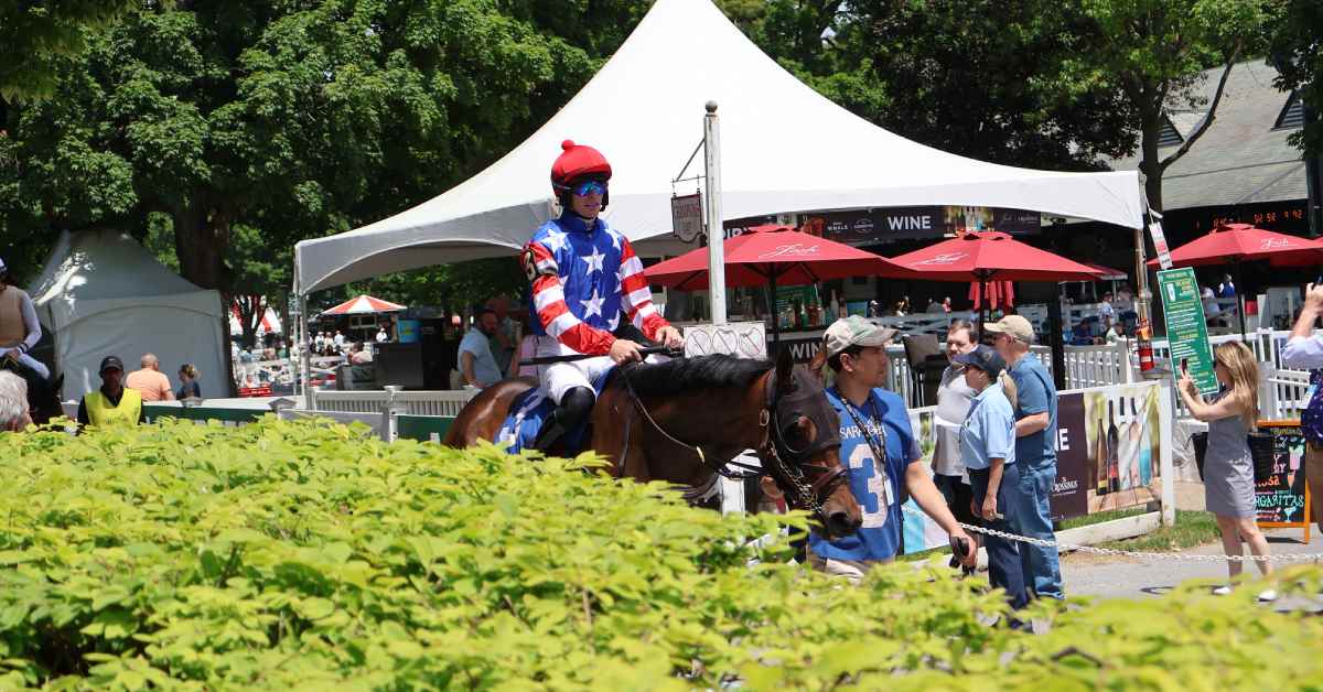 jockey riding on a horse along walking path