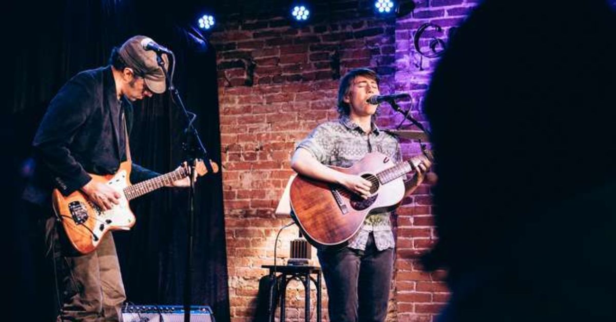 man singing with guitar and another man playing guitar