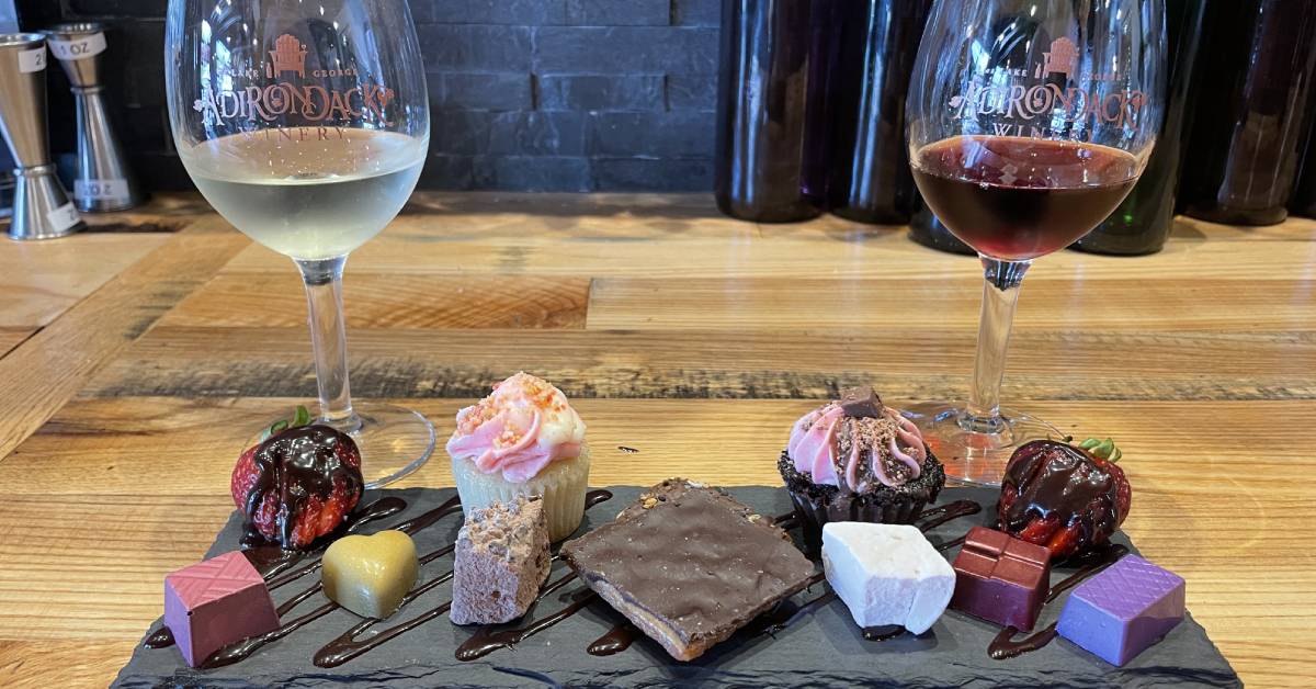 desserts on a platter next to red and white glasses of wine