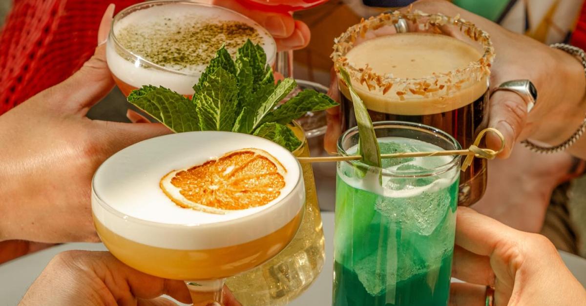 four colorful cocktail drinks held close to each other