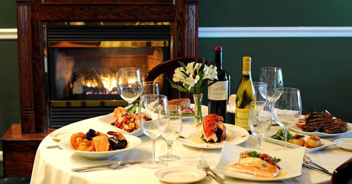 restaurant dining room table with drinks and food, and a fireplace in the back