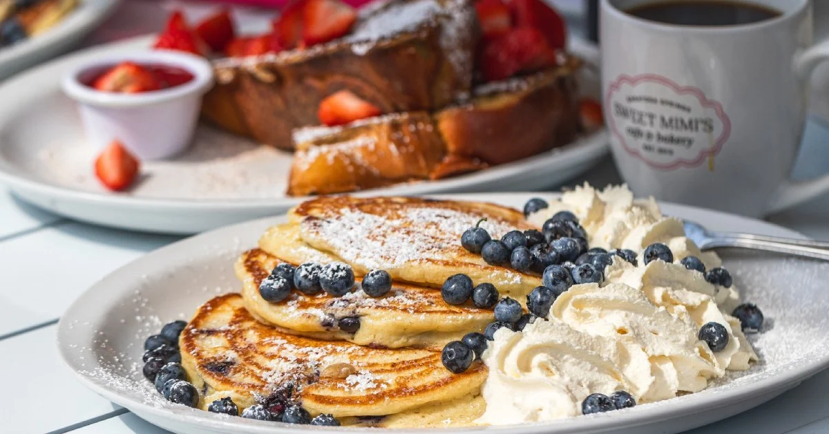 pancakes with blueberries on them with french toast in the background