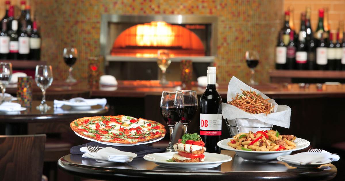 pizza and Italian dishes on a table with wine glasses
