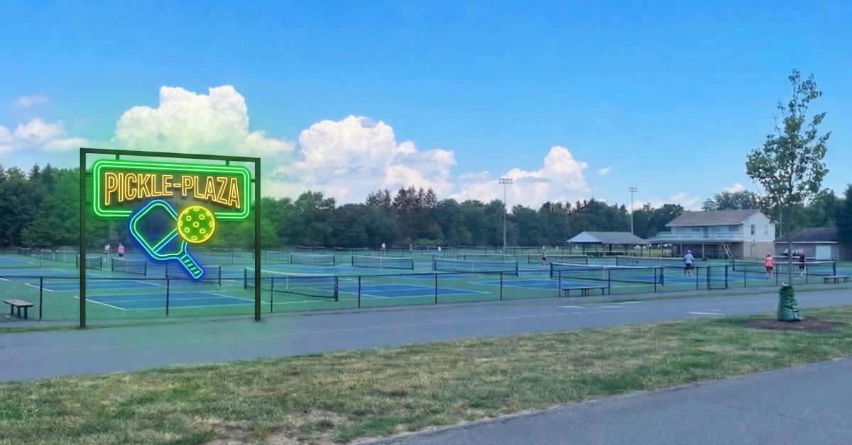 a park area filled with pickleball courts and a neon sign