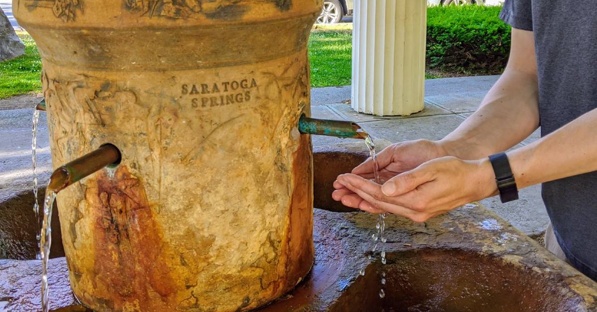 hands cupping water from mineral spring