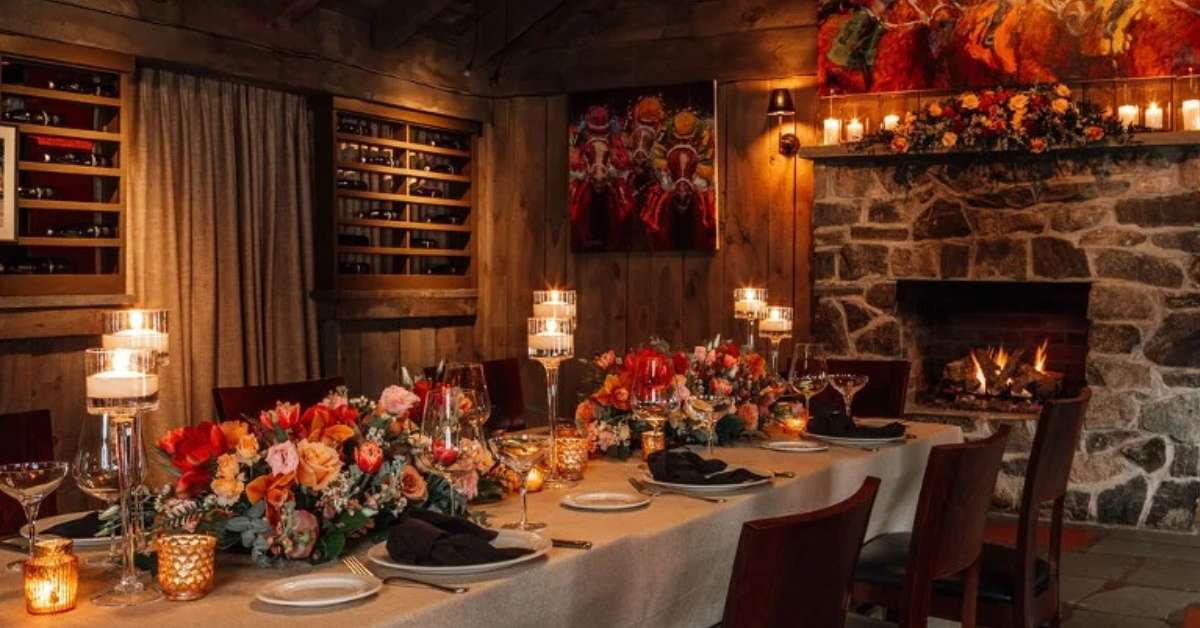 a table with glassware and silverware on it next to a stone fireplace