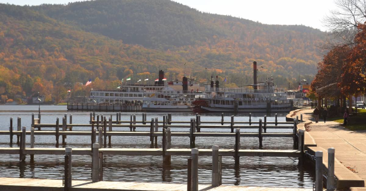 Lake George steamboat cruising on the water with village shoreline and Adirondack Mountains in the background