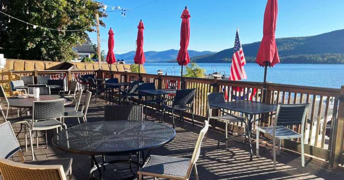 Deck seating at The Lagoon in Lake George with patio tables, red umbrellas, and waterfront views along the railing