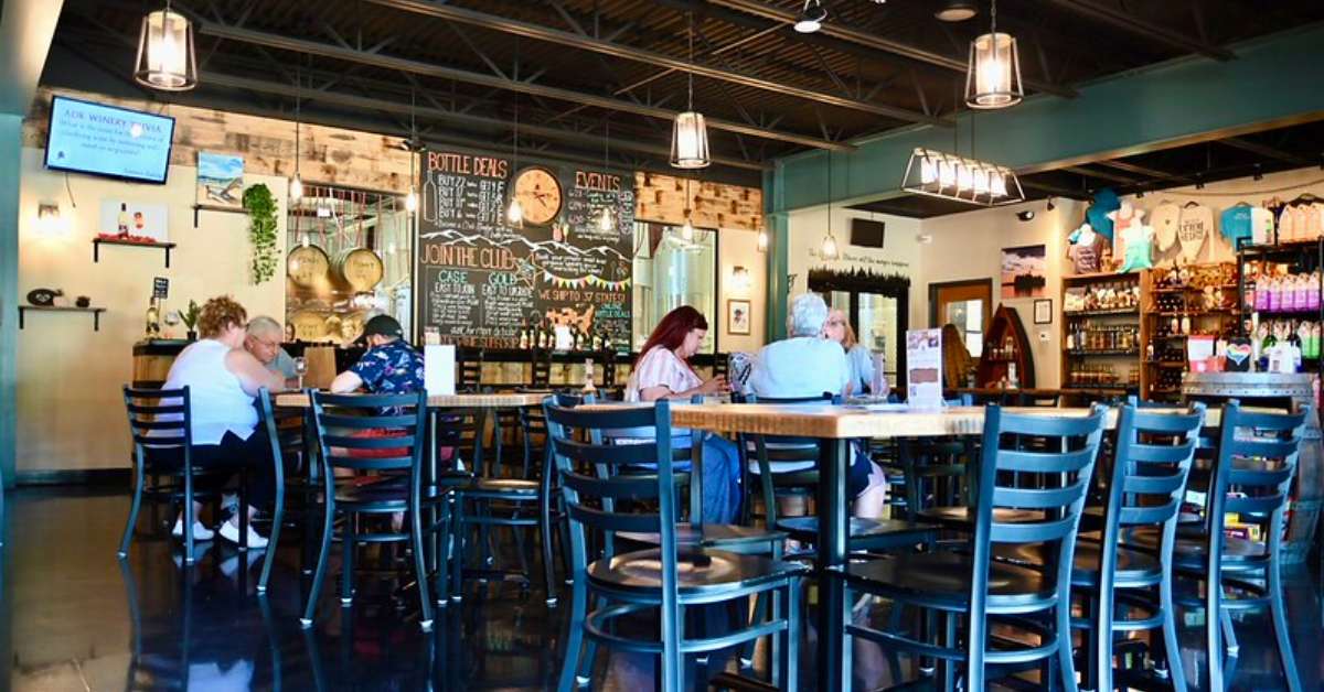 people sitting at tables inside adk winery