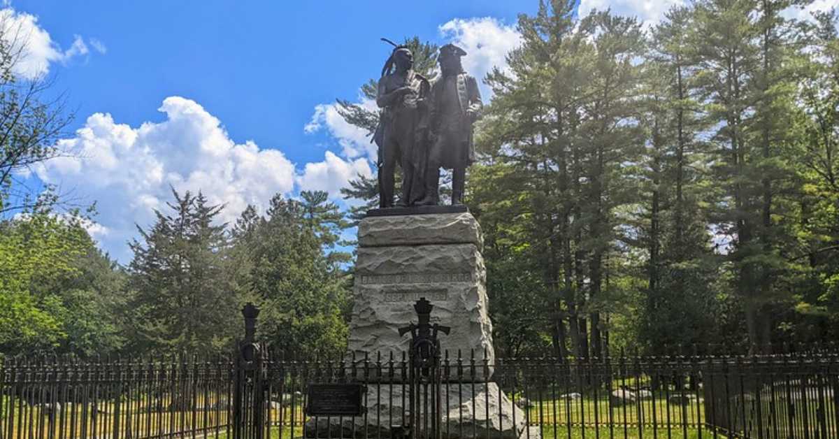 statue with two figures on it in front of trees