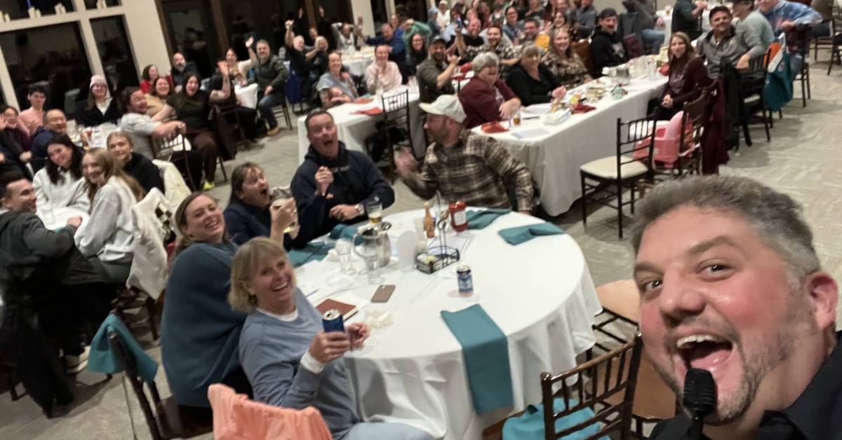 host of trivia night event takes a selfie with crowd