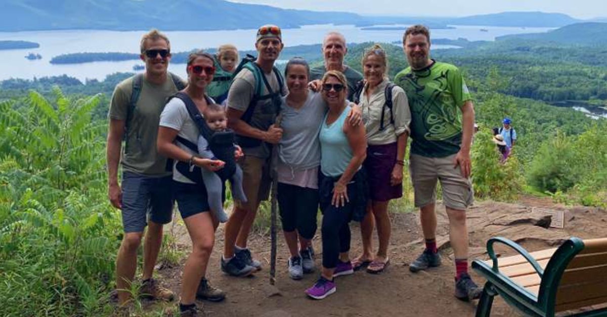 people posing on top of mountain in front of view.