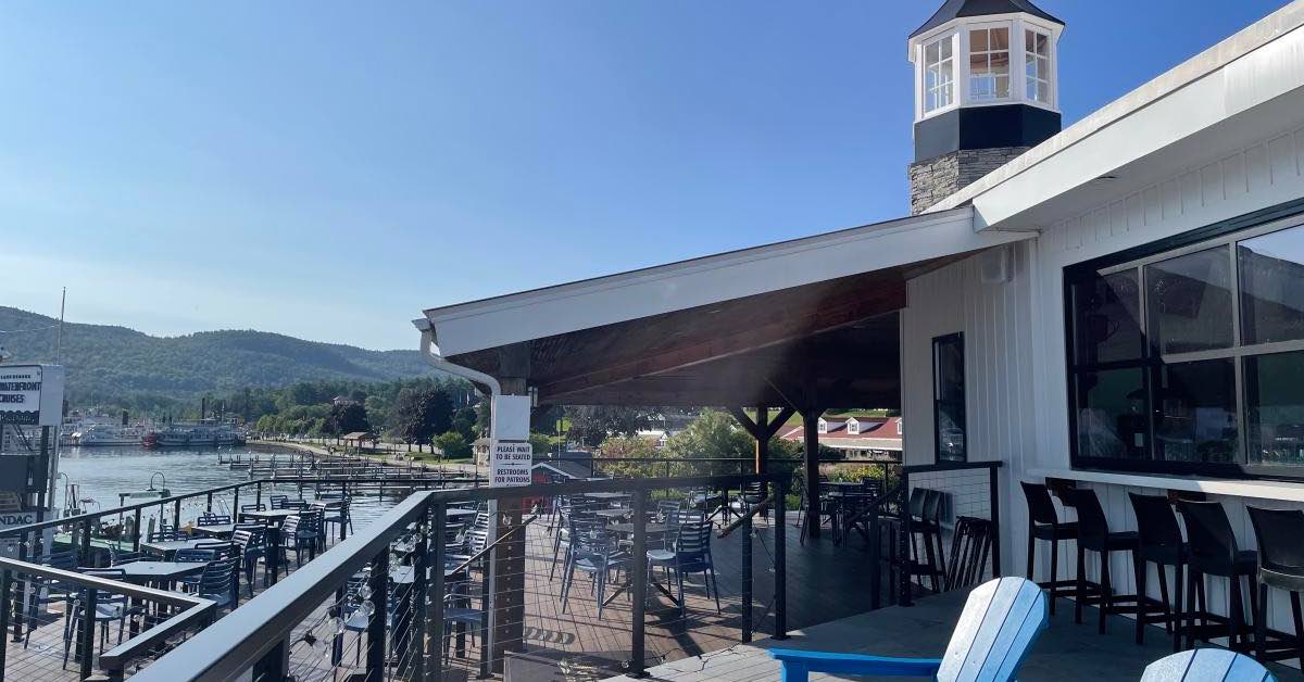 Outdoor deck at Lighthouse Grill in Lake George with bar seating, tables, and view of the waterfront