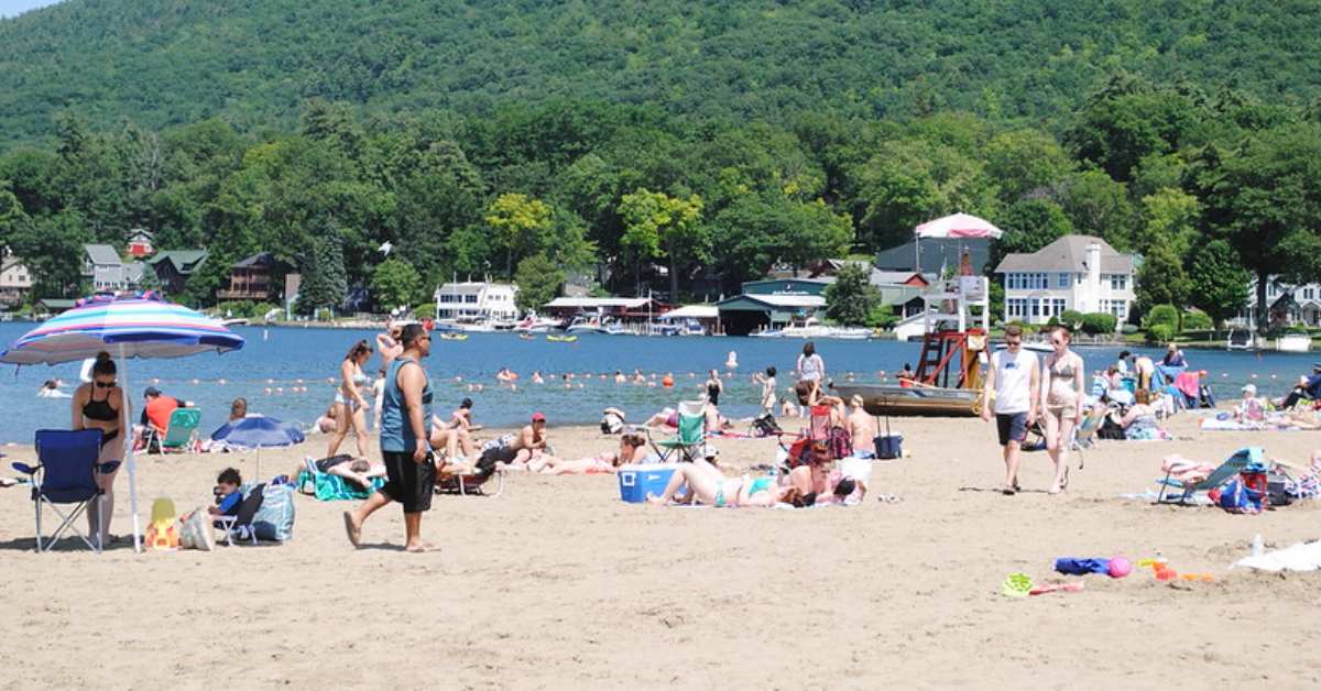 a large crowd of people on a sandy lake beach