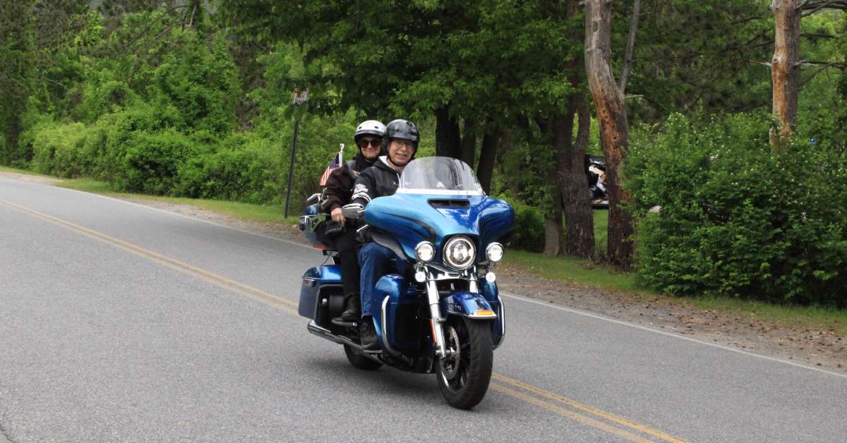 man and woman on a blue motorcycle driving down road
