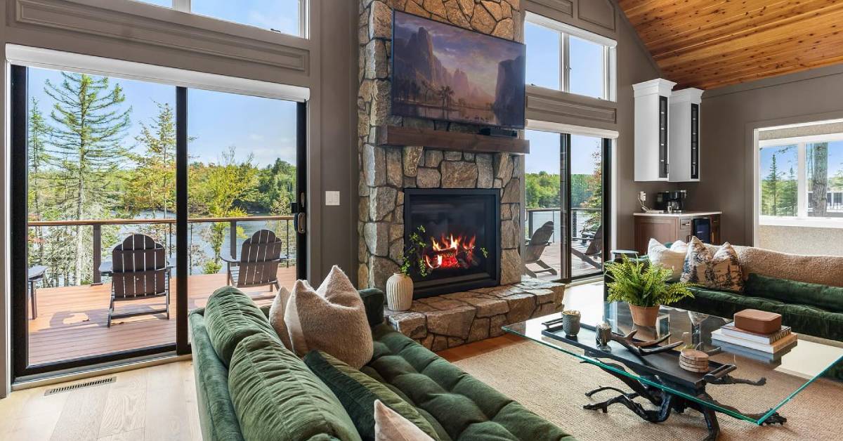 fire in fireplace at rental house with floor to ceiling windows overlooking lake
