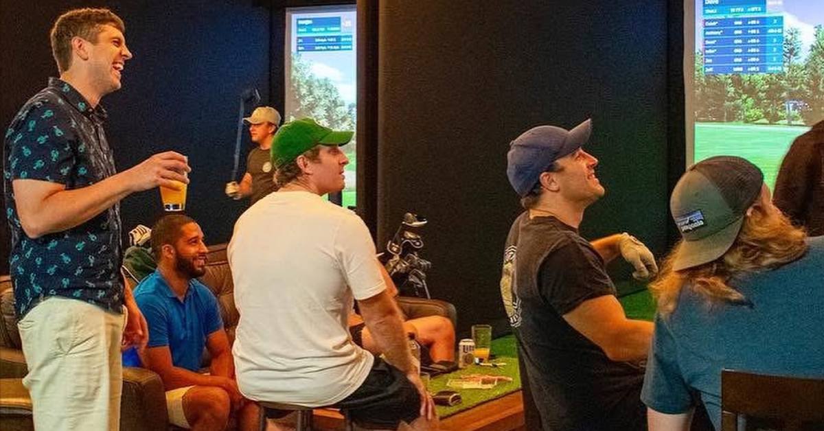 a group of guys at indoor golf sims