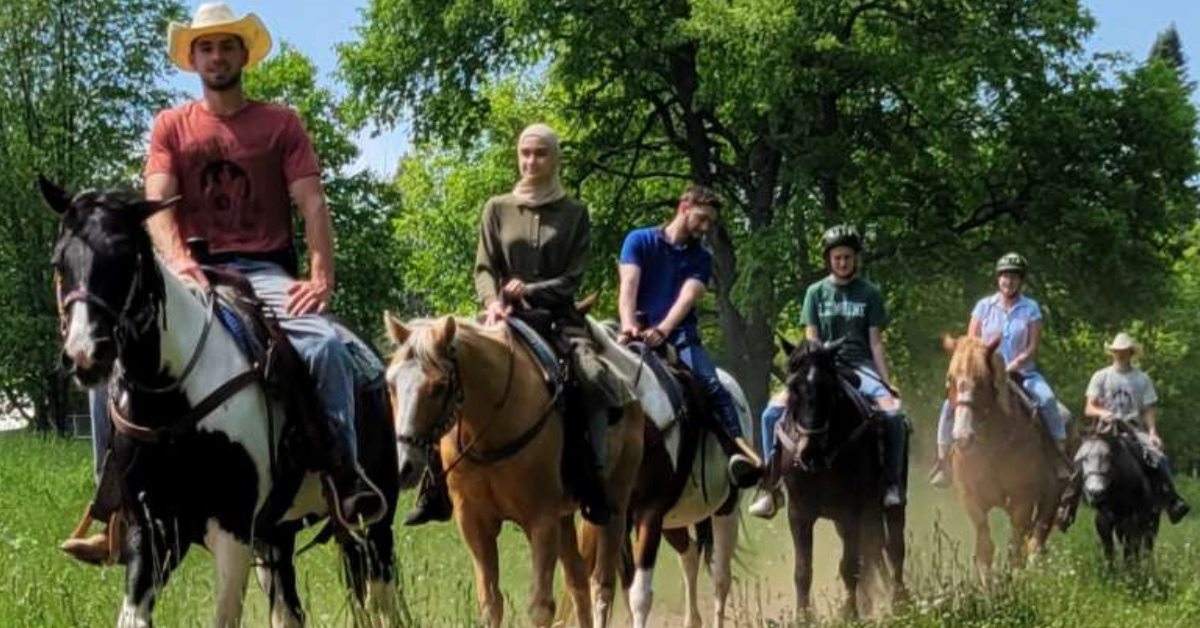 people riding on horses along a grassy trail