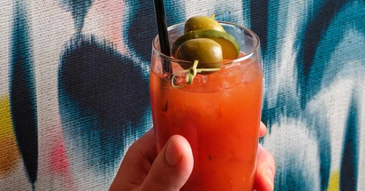 bloody mary with olives on it in front of a background