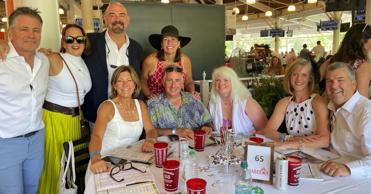 a group dressed nicely in a horse racetrack indoor viewing room
