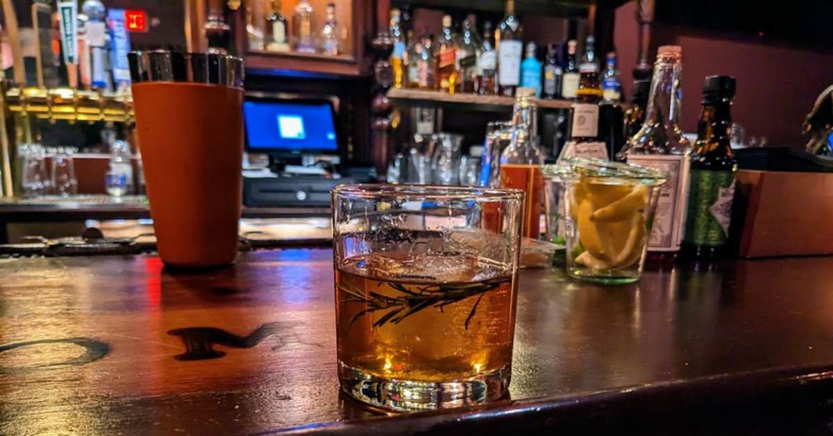 a glass of bourbon on a bar