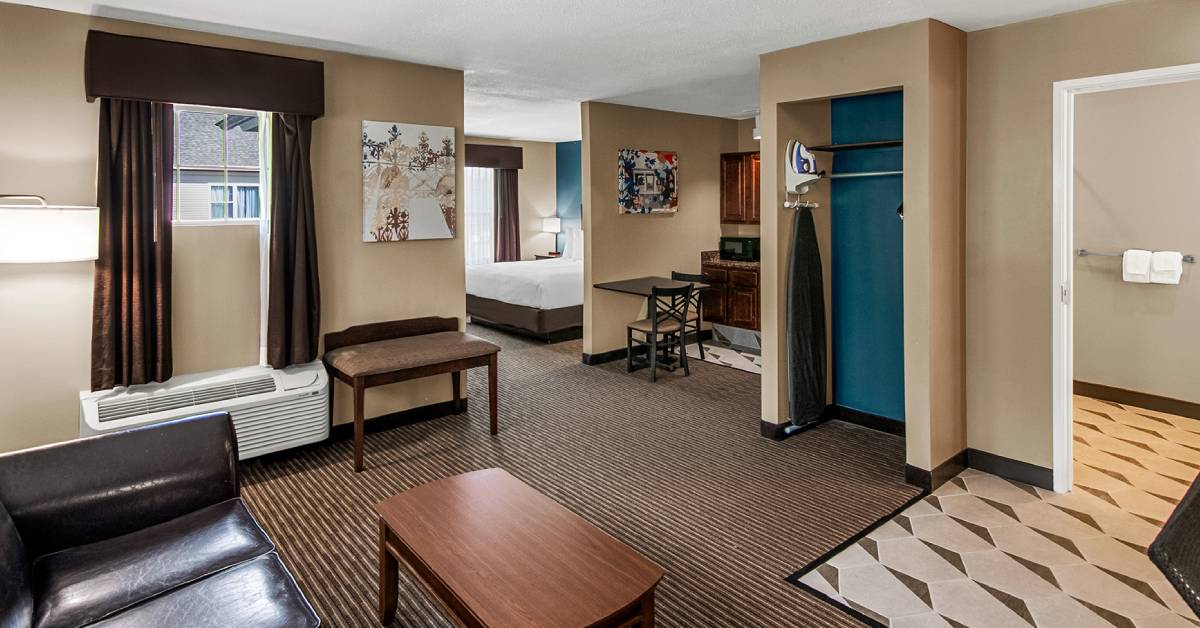 a spacious hotel suite with bed, kitchen, and seating area