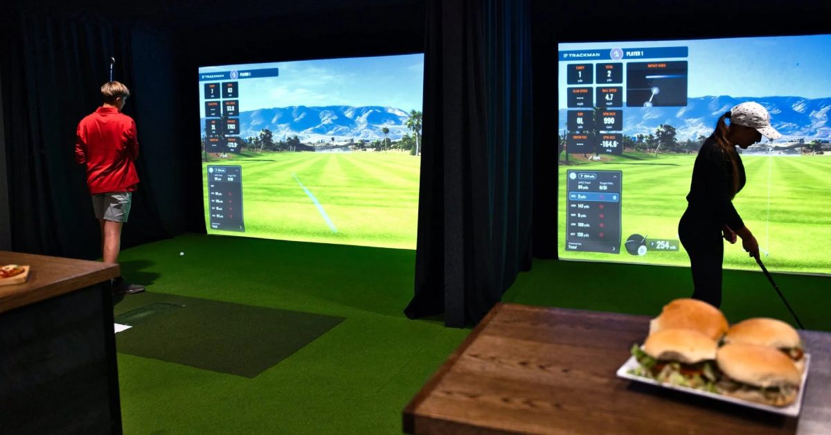 two people at indoor golf simulators