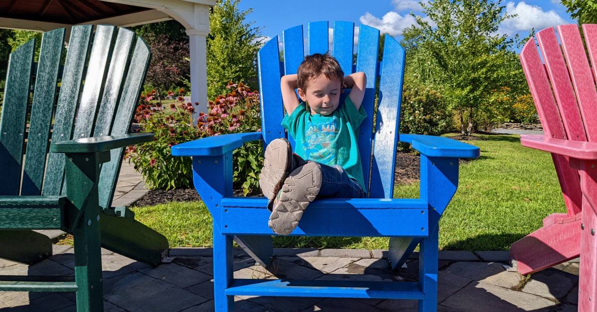 kid in blue adirondack chair in park