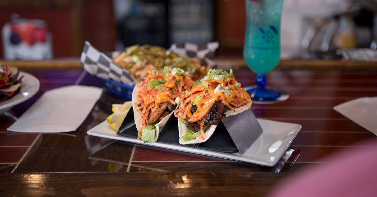 tacos on a tray with a beverage in the background
