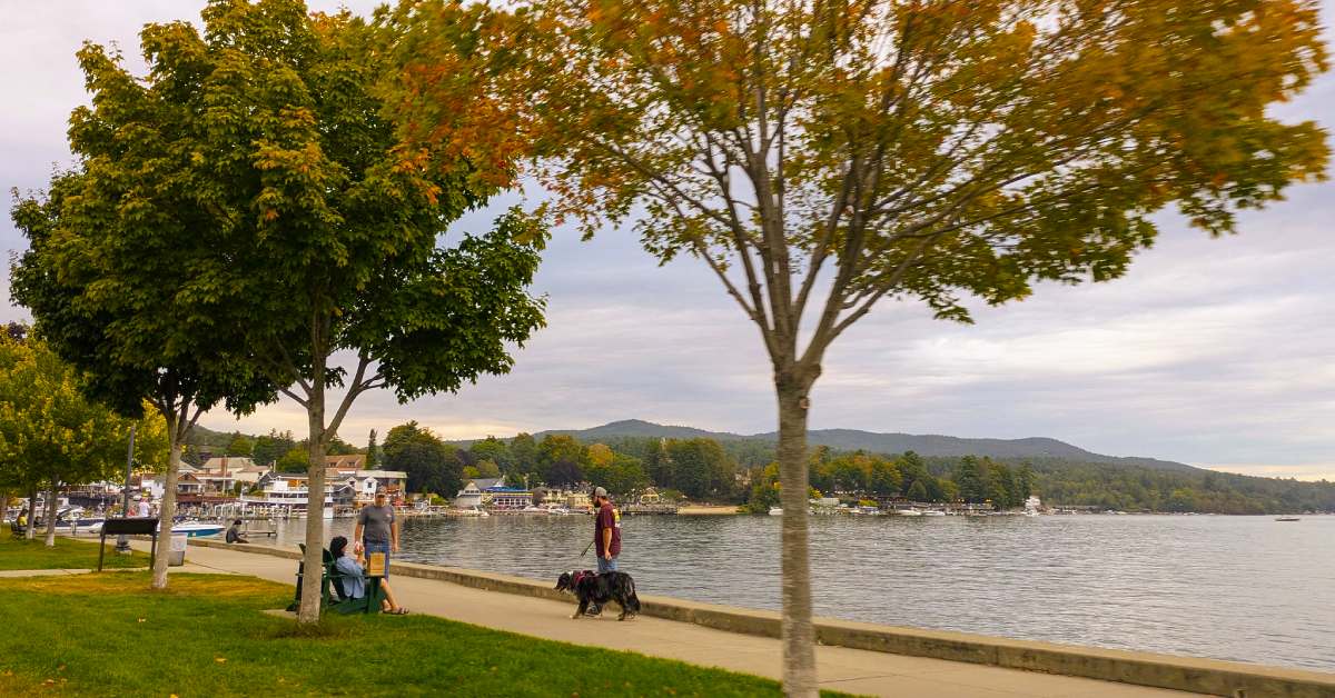 a few people walking by the lake shoreline during late afternoon fall day