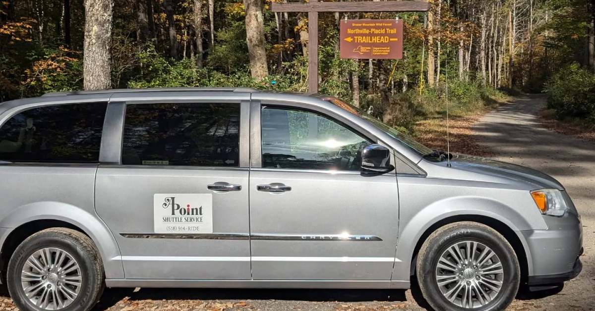 APoint Shuttle Van by a trail sign