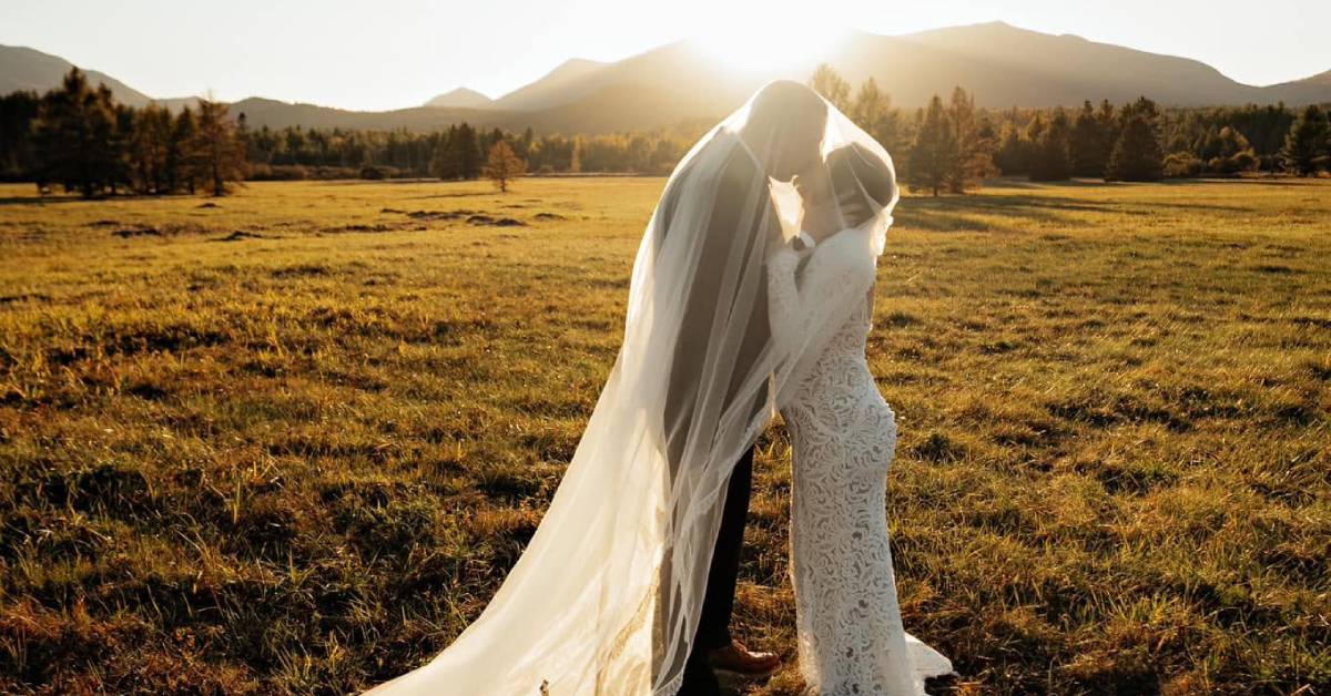 bride and groom in field at sunset