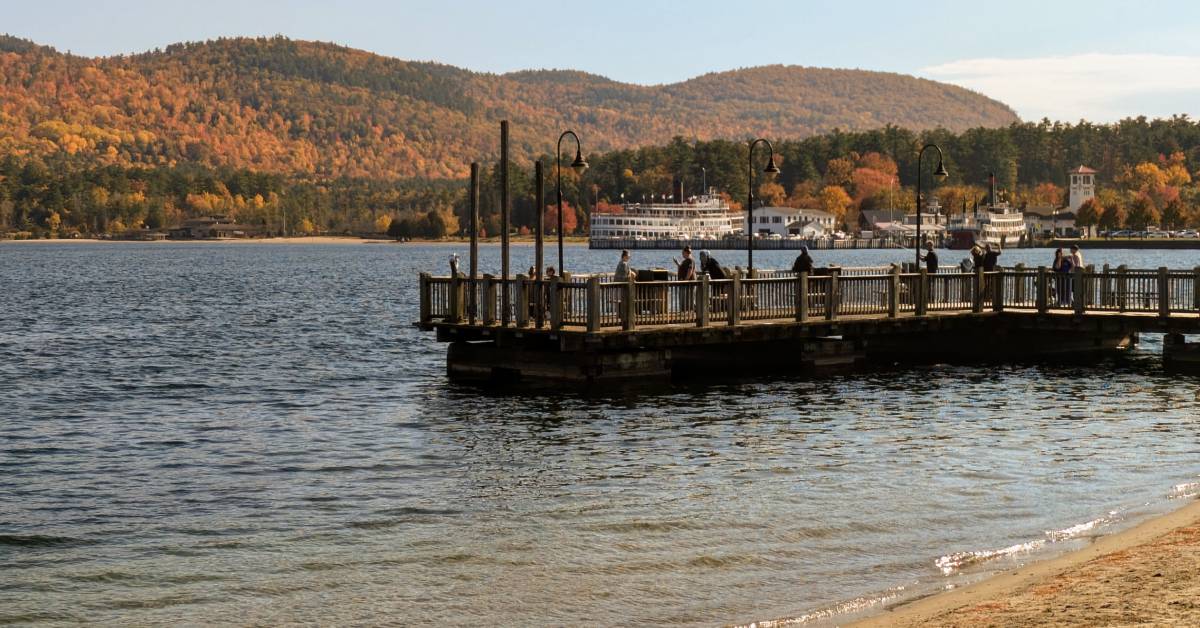 people on lake george docks taking photos of foliage